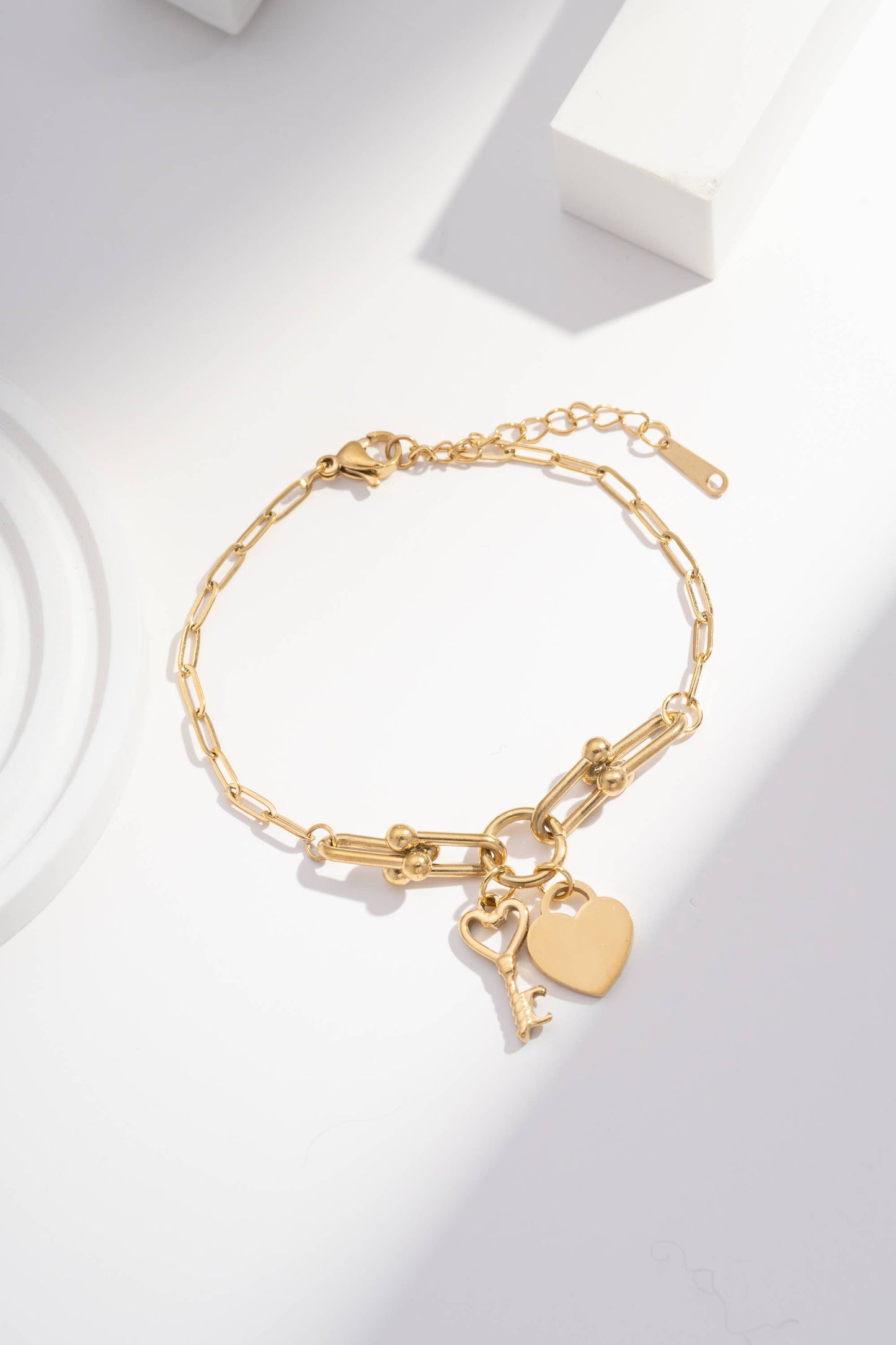 Verstellbares goldenes Kettenarmband mit Herz- und Schlüsselanhängern aus Stahl.